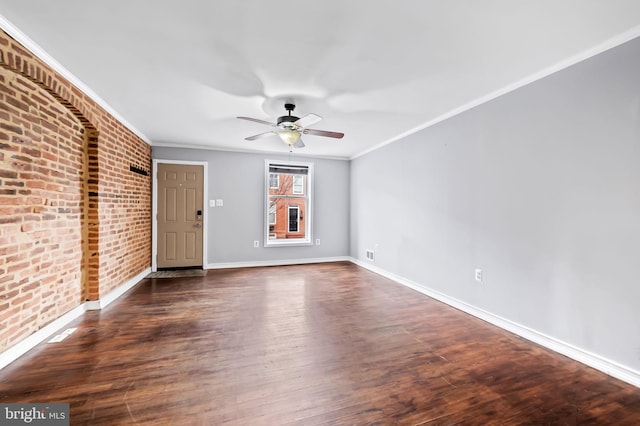 spare room featuring ceiling fan, dark hardwood / wood-style flooring, brick wall, and ornamental molding