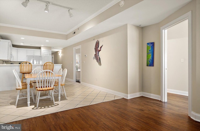 unfurnished dining area featuring rail lighting, crown molding, and light hardwood / wood-style flooring