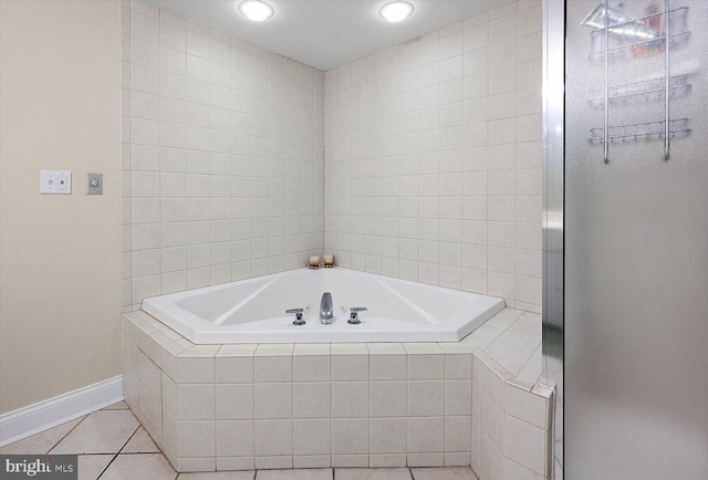 bathroom with tiled tub and tile patterned flooring