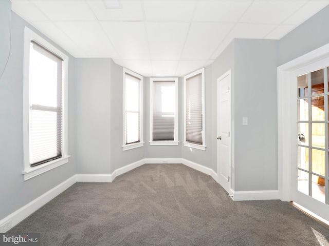 empty room with a paneled ceiling and carpet flooring