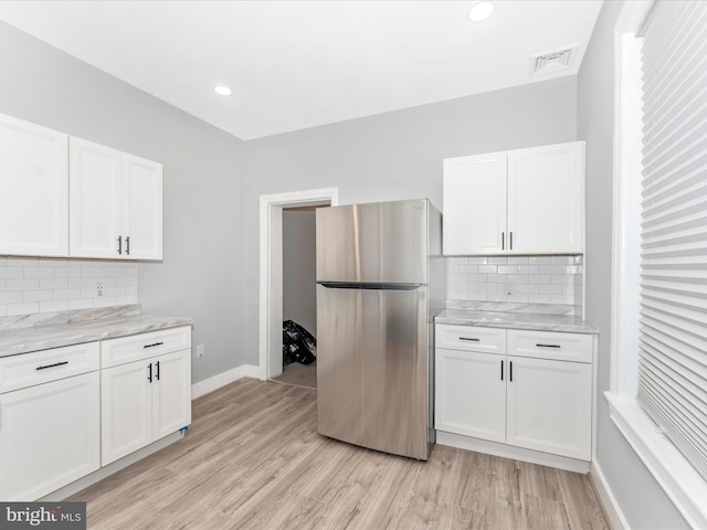 kitchen with white cabinetry, stainless steel refrigerator, and light hardwood / wood-style flooring