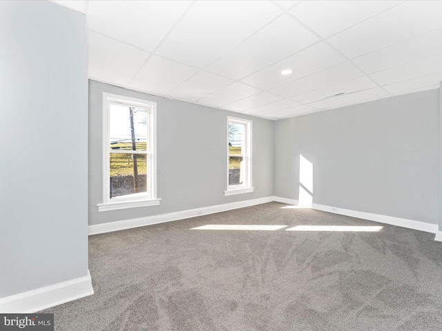 empty room featuring carpet flooring and a paneled ceiling