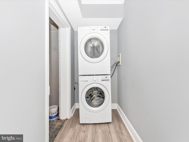 laundry room featuring light wood-type flooring and stacked washer and clothes dryer