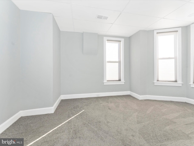 carpeted empty room featuring a drop ceiling