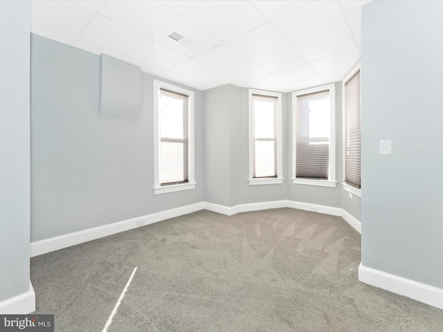 carpeted empty room with a paneled ceiling and plenty of natural light