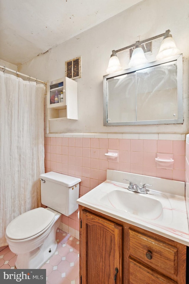 bathroom with vanity, toilet, and tile walls