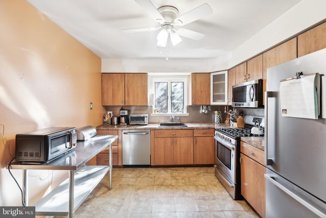 kitchen featuring ceiling fan, sink, tasteful backsplash, light stone counters, and appliances with stainless steel finishes