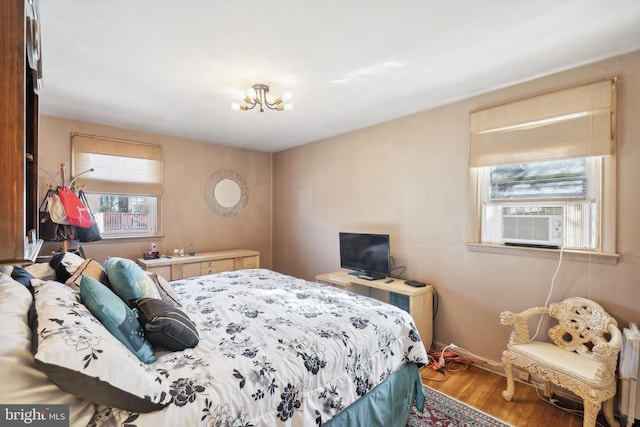 bedroom with hardwood / wood-style flooring, an inviting chandelier, and cooling unit