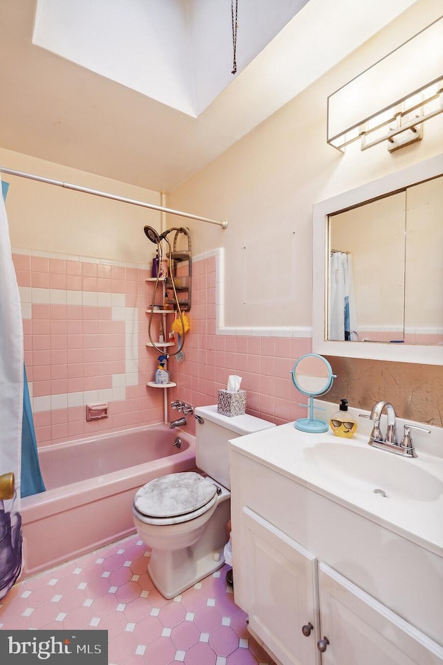 full bathroom with shower / bath combo, toilet, tile walls, and vanity