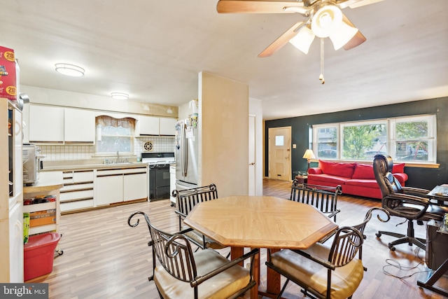 dining space with ceiling fan and light hardwood / wood-style flooring