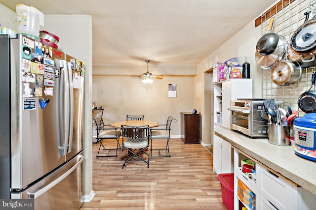 kitchen with stainless steel fridge, light wood-type flooring, white cabinetry, and ceiling fan