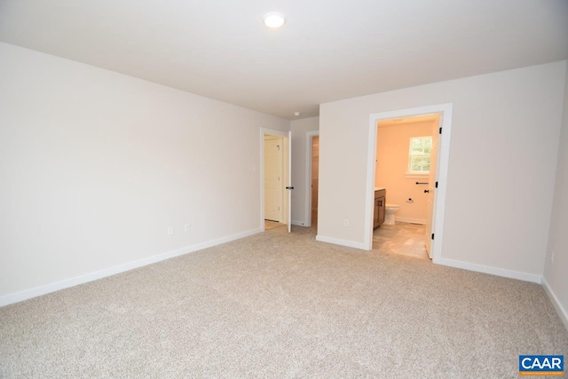 unfurnished bedroom featuring connected bathroom and light colored carpet