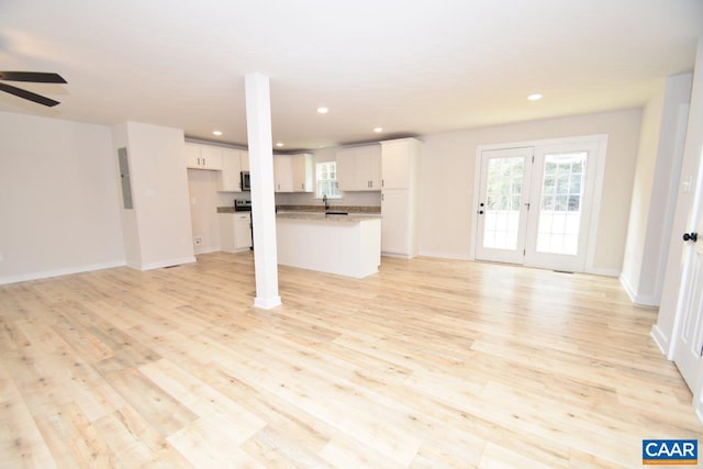 unfurnished living room featuring french doors, light wood-type flooring, ceiling fan, sink, and electric panel