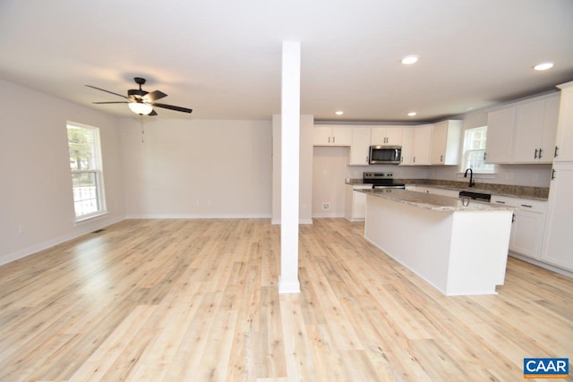 kitchen featuring appliances with stainless steel finishes, light wood-type flooring, white cabinetry, and a kitchen island