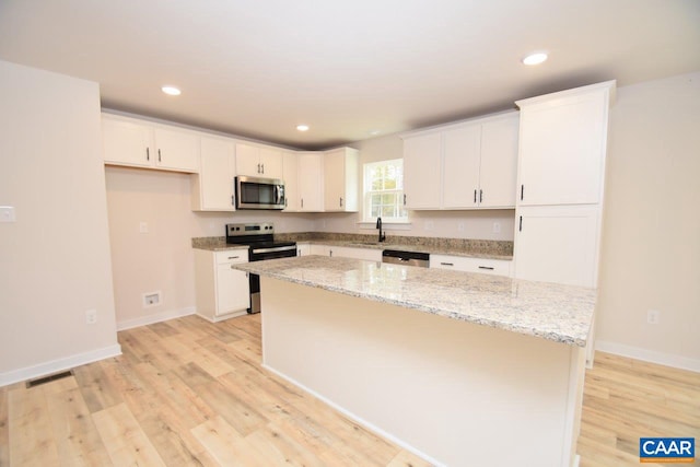 kitchen featuring white cabinetry, a center island, stainless steel appliances, and light hardwood / wood-style floors