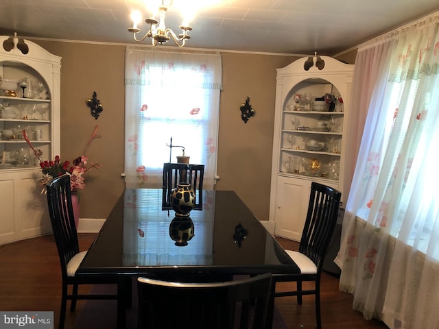 dining room with dark wood-type flooring, ornamental molding, and a notable chandelier