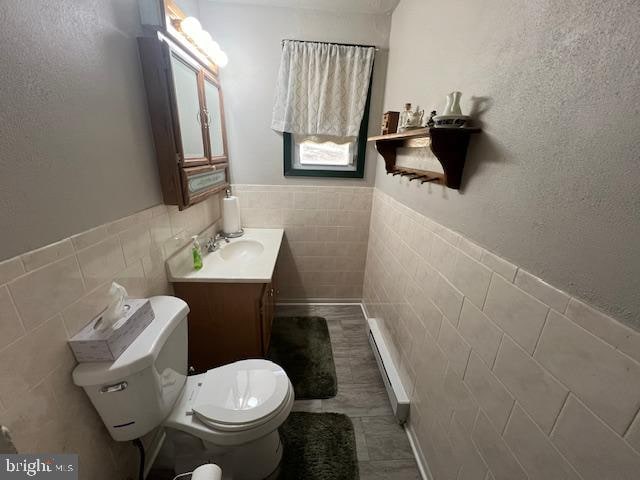 bathroom with vanity, toilet, tile walls, and a baseboard radiator