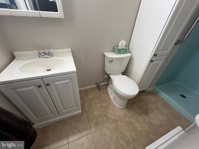 bathroom with tile patterned floors, vanity, toilet, and walk in shower