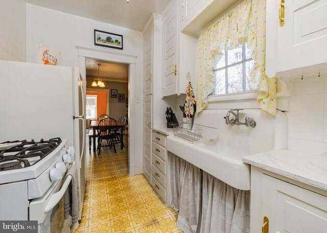 kitchen with white cabinets, white range with gas stovetop, hanging light fixtures, and a healthy amount of sunlight