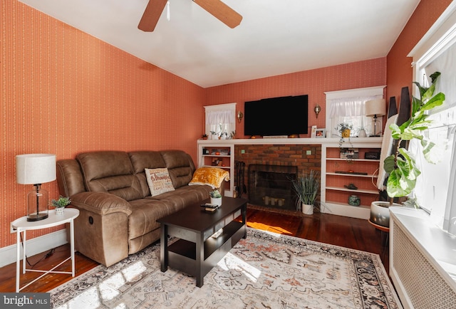 living room featuring hardwood / wood-style floors, ceiling fan, and a fireplace