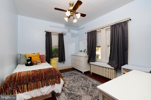 bedroom with dark hardwood / wood-style flooring, radiator heating unit, and ceiling fan