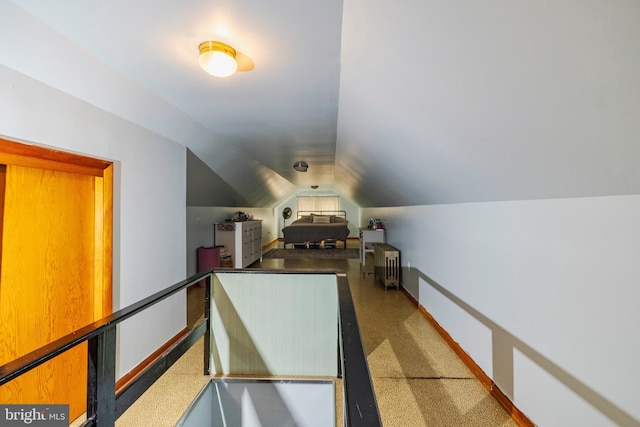 additional living space with vaulted ceiling and dark colored carpet