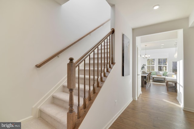 stairs featuring wood-type flooring and a notable chandelier