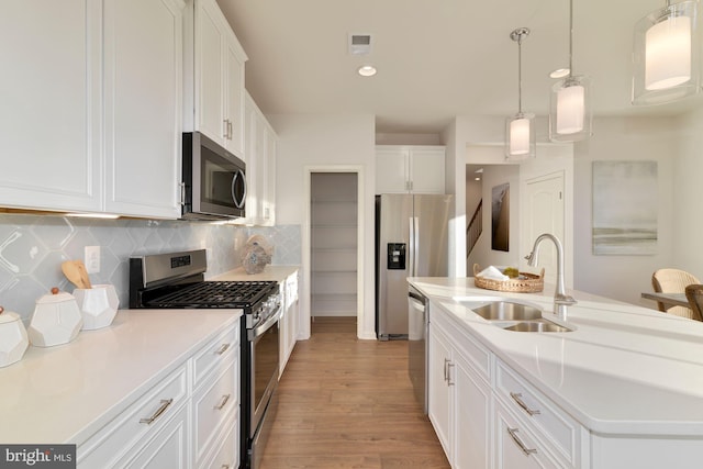 kitchen featuring a kitchen island with sink, appliances with stainless steel finishes, sink, and white cabinets