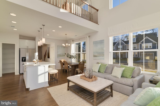 living room featuring a towering ceiling, dark hardwood / wood-style floors, a chandelier, and sink