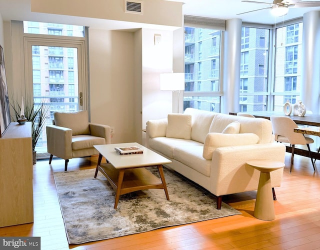 interior space with expansive windows, ceiling fan, and light wood-type flooring