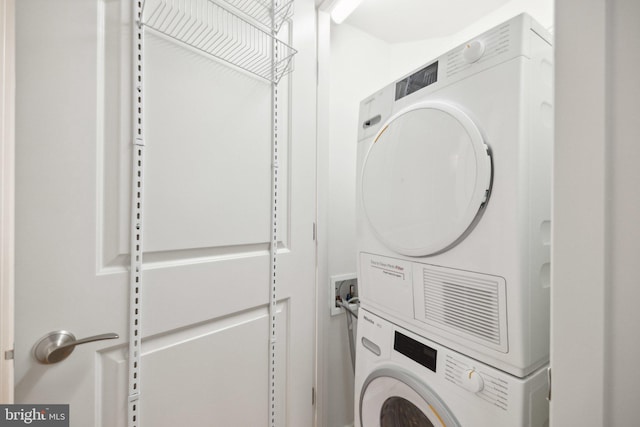 clothes washing area featuring stacked washing maching and dryer