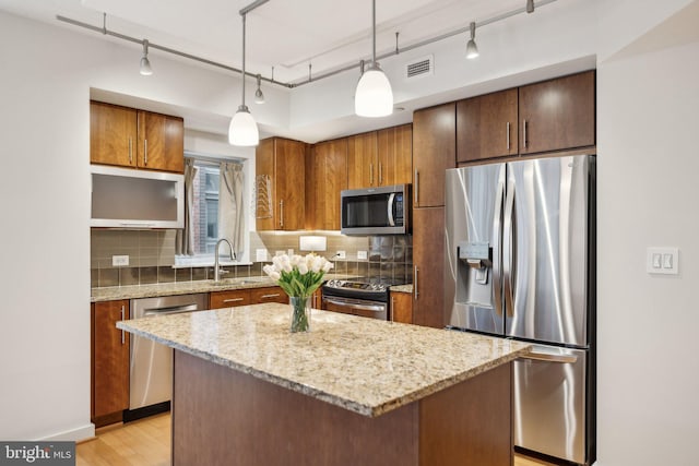 kitchen featuring sink, stainless steel appliances, a center island, tasteful backsplash, and decorative light fixtures