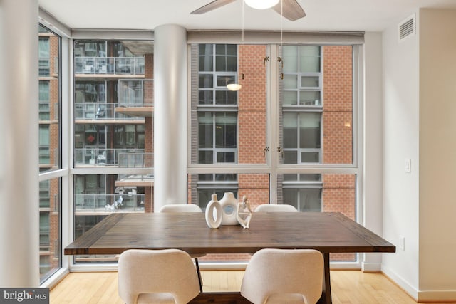 dining room with hardwood / wood-style floors, plenty of natural light, expansive windows, and ceiling fan