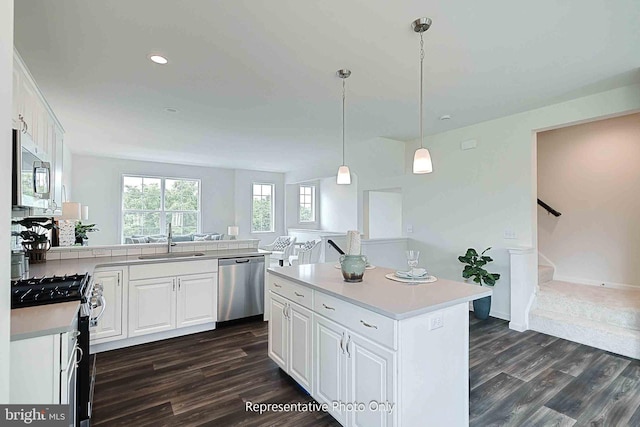 kitchen with white cabinets, stainless steel appliances, dark hardwood / wood-style floors, and a kitchen island