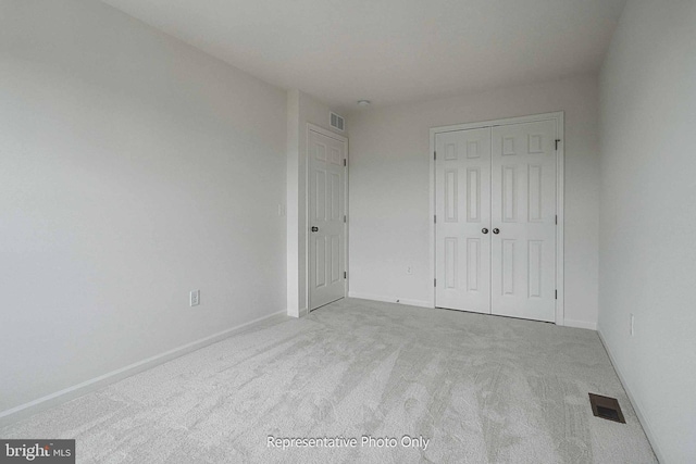 unfurnished bedroom with light colored carpet and a closet