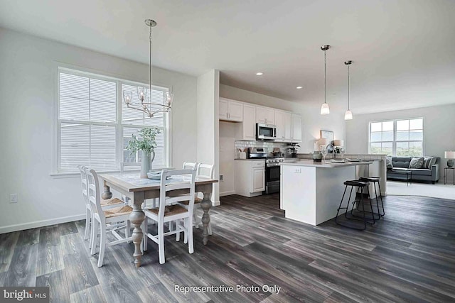 kitchen featuring dark hardwood / wood-style flooring, appliances with stainless steel finishes, decorative light fixtures, and white cabinets