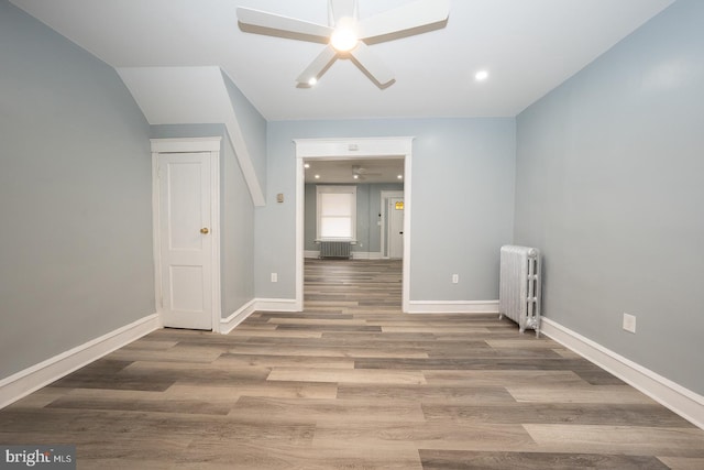 unfurnished room featuring radiator heating unit, ceiling fan, and wood-type flooring