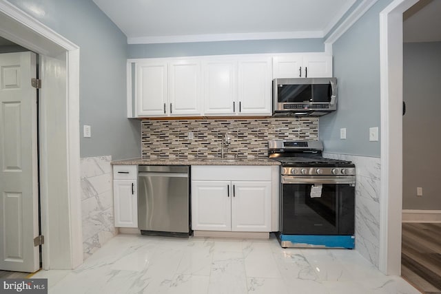 kitchen featuring white cabinetry, sink, crown molding, dark stone counters, and appliances with stainless steel finishes