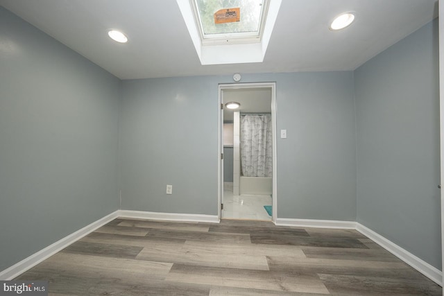 unfurnished room featuring wood-type flooring and a skylight