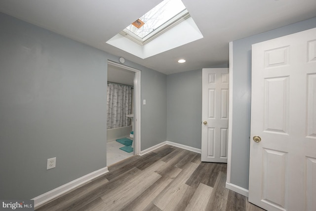 spare room with hardwood / wood-style floors and a skylight