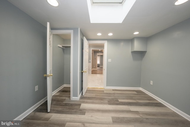 unfurnished bedroom with a skylight, a closet, and hardwood / wood-style flooring