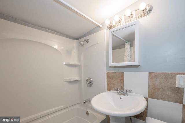 bathroom featuring tile walls, sink, shower / bath combo, and lofted ceiling