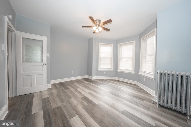 unfurnished room featuring radiator heating unit, light hardwood / wood-style floors, and ceiling fan