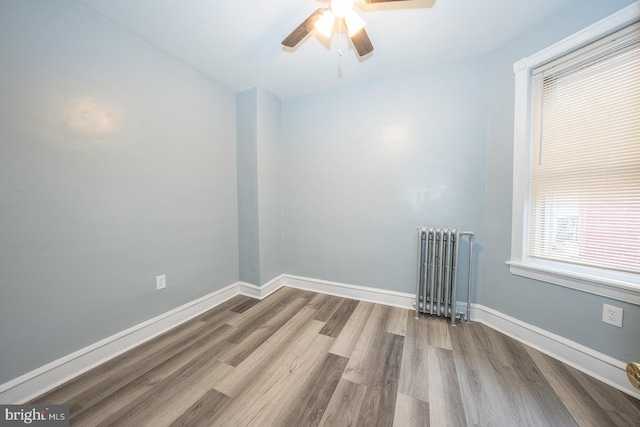 spare room featuring ceiling fan, radiator heating unit, and hardwood / wood-style floors