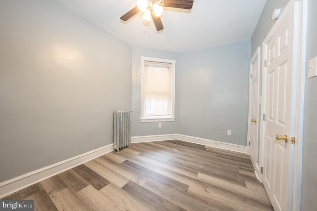 unfurnished room with ceiling fan, radiator, and light hardwood / wood-style flooring