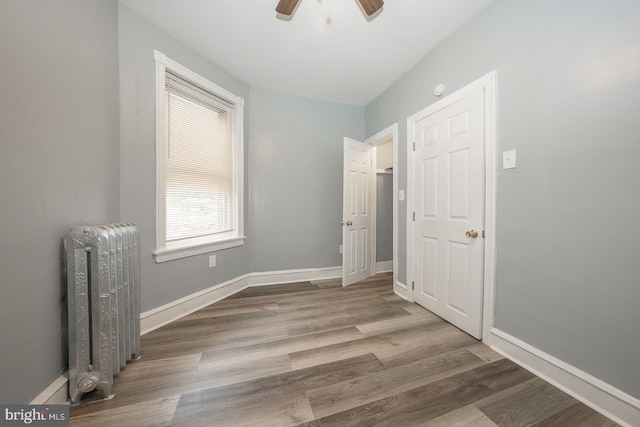 interior space with wood-type flooring, radiator, and ceiling fan