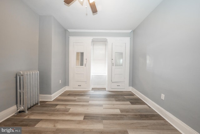 unfurnished room featuring ceiling fan, radiator heating unit, and hardwood / wood-style floors