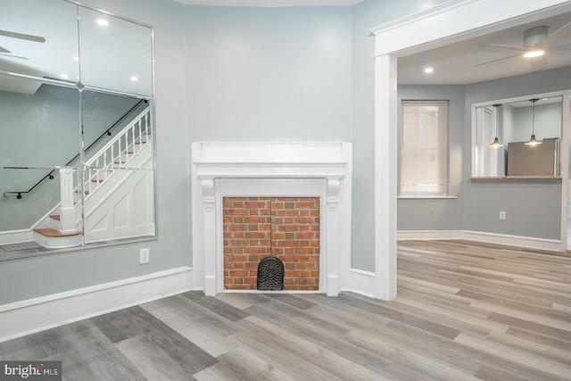 unfurnished living room featuring ceiling fan, light hardwood / wood-style floors, and a brick fireplace