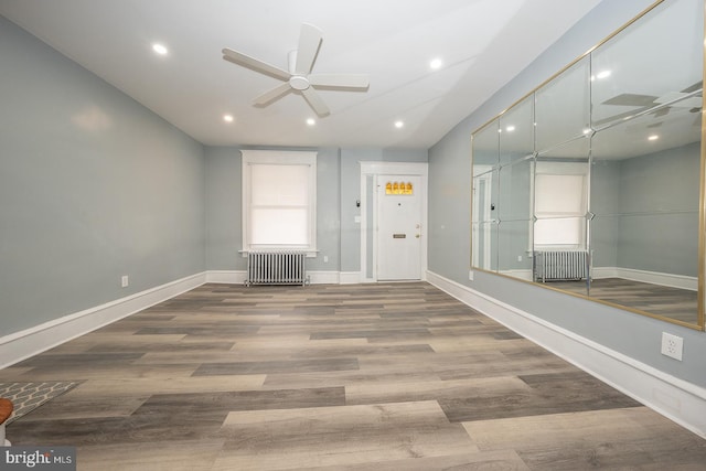 foyer with hardwood / wood-style floors, ceiling fan, and radiator