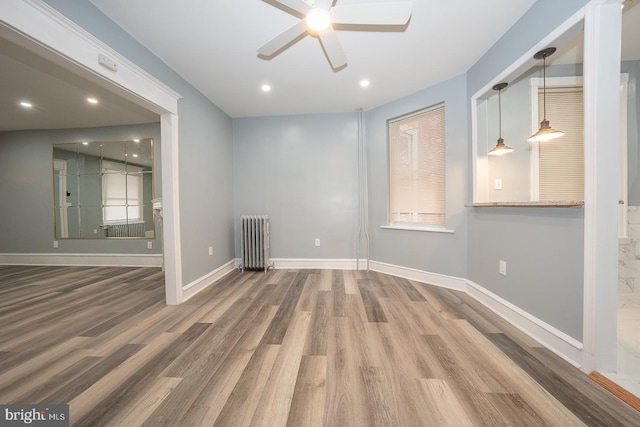 unfurnished room featuring radiator heating unit, ceiling fan, and hardwood / wood-style floors